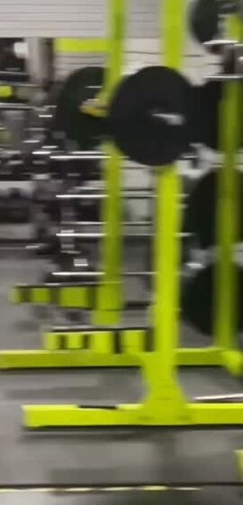 Lime-green squat racks loaded with weight plates on the gym floor
