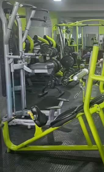 Lime-green and grey plate-loaded machines lined up along the gym